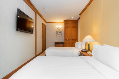 a hotel room with two beds and a television at Grand Diamond Suites Hotel in Bangkok