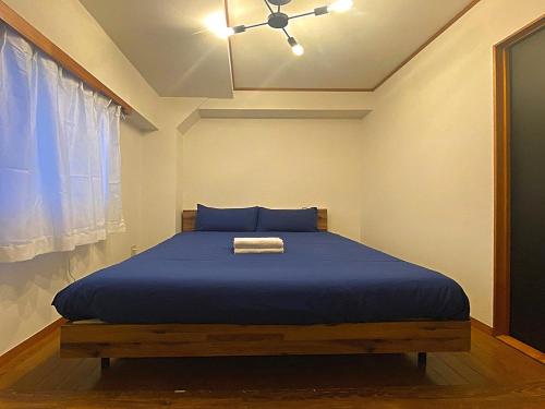 a bedroom with a bed with blue sheets and a ceiling at Ema eve HOUSE in Tokyo