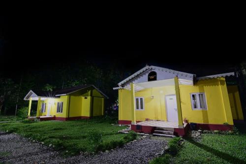 a row of small yellow houses at night at Townhouse OAK Gorumara Jungle Resort in Chālsa Mahābāri