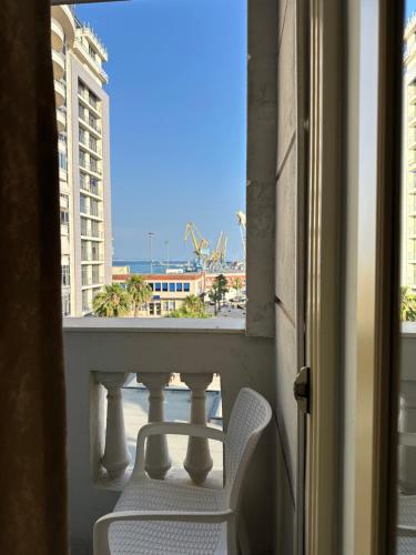 a white chair sitting on a balcony with a view of a building at Hotel Veliera in Durrës