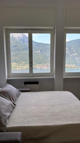a bedroom with two large windows and a bed at Monolocale Riva Lake in Valbrona