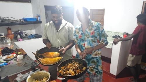 a man and a woman standing in a kitchen preparing food at Nilaveli house Stay in Kumpurupiddi