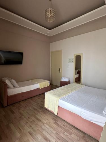 a bedroom with two beds and a tv on the wall at Hotel Veliera in Durrës
