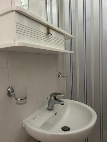 a white sink in a bathroom with shelves at Appartamenti Vacanze Minervino in Vieste