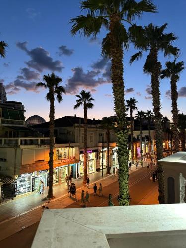 a street with palm trees in a city at night at Hotel Veliera in Durrës