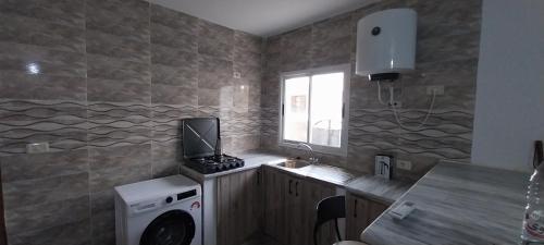 a kitchen with a washing machine and a window at Studio SARAH in Tabarka