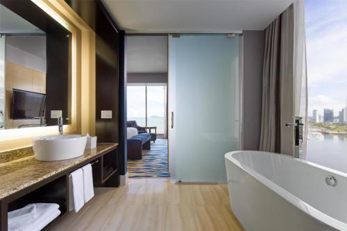 a bathroom with a bath tub and a large mirror at Hilton Panama in Panama City