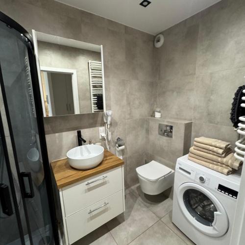 Un baño con lavadora y un inodoro. en Lubelska SkyRes City View & Free Parking, en Rzeszów