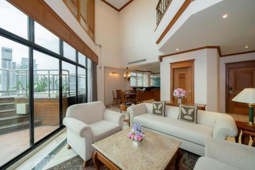 a living room with white furniture and a large window at Grand Diamond Suites Hotel in Bangkok