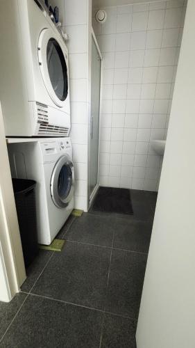 a small bathroom with a washing machine and a washer at Bruggeske aan't bos in Mol