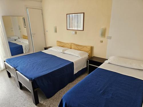 a hotel room with two beds and a mirror at Hotel Riviera Nuova Gestione in Cattolica