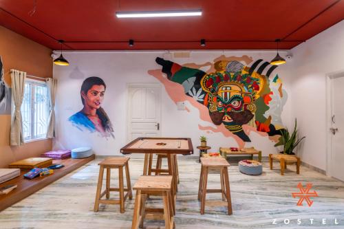 a room with a mural on the wall and stools at Zostel Chennai, Anna Nagar in Chennai