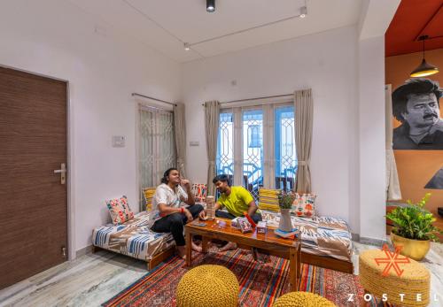 two men sitting on a couch in a living room at Zostel Chennai, Anna Nagar in Chennai
