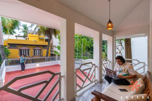 a woman sitting on the porch of a house at Zostel Chennai, Anna Nagar in Chennai