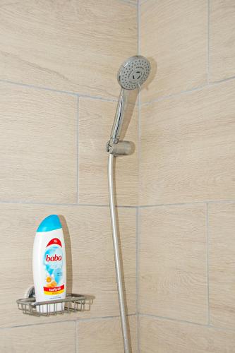 a shower with a bottle of cleaner on a shelf at Tiszafa Vendégház Nagykanizsa in Nagykanizsa