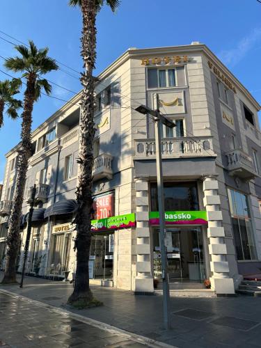 a building on a city street with a palm tree at Hotel Veliera in Durrës