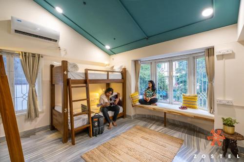 two women sitting in a room with bunk beds at Zostel Chennai, Anna Nagar in Chennai