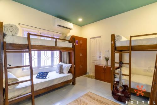 a room with bunk beds with a guitar in it at Zostel Chennai, Anna Nagar in Chennai