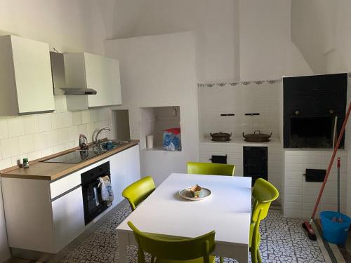 a kitchen with a white table and yellow chairs at Casa Sole - Cursi in Cursi
