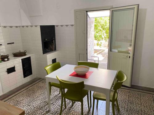 a kitchen with a white table and green chairs at Casa Sole - Cursi in Cursi