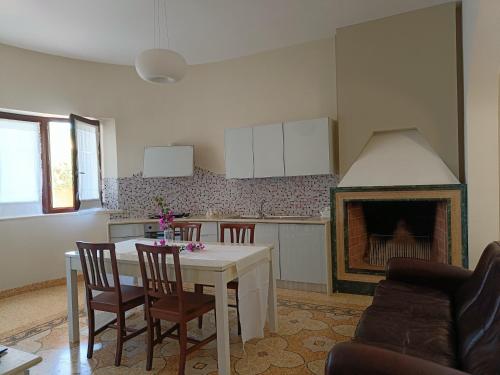una cucina con tavolo, sedie e camino di Dimora del Sole Salento a Taurisano