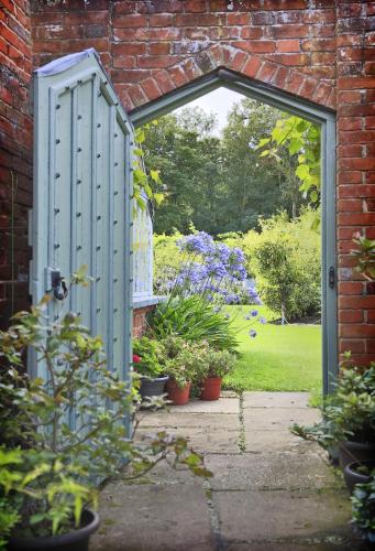 an open door into a garden with potted plants at Garden View in Parham