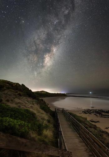 a starry night over a beach with a wooden boardwalk at Tropicana Motor Inn in Cowes