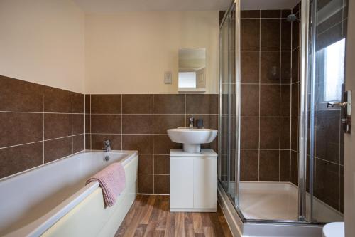 a bathroom with a tub and a sink and a shower at Boyton House Sleeps 14 Long Stays Parking Wi-Fi in Swindon