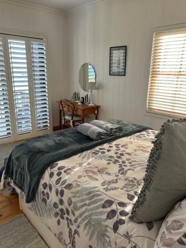 a bedroom with a bed and a table and windows at Shick-Shack in Eersterivierstrand