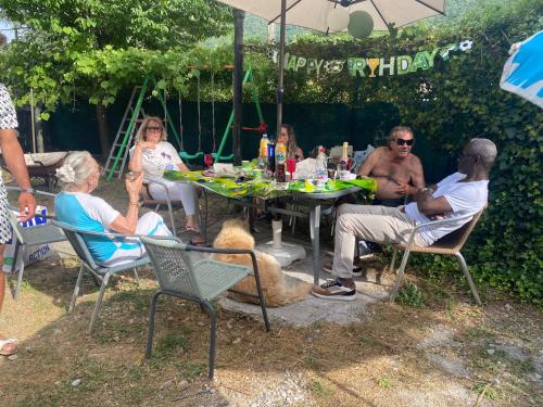 Un groupe de personnes assises autour d'une table sous un parapluie dans l'établissement Maison de campagne 1 à 18 couchages et plus, à Roquestéron