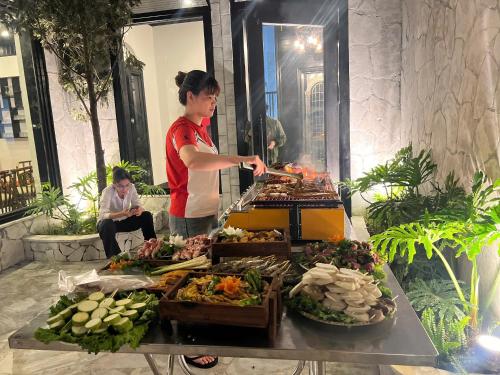 a woman cooking food on a table with vegetables at Sapa Villa Florence in Sa Pa