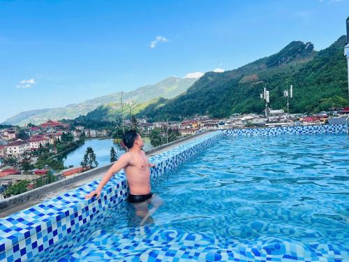 a man in a swimming pool with a view of a city at Sapa Villa Florence in Sa Pa