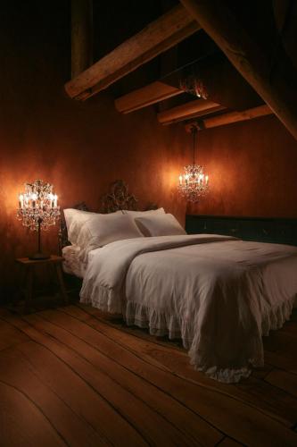 a bedroom with a bed with white sheets and chandeliers at Castelul de Lut - Eco Boutique Guesthouse in Porumbacu de Sus