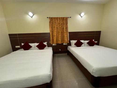 two beds in a room with red pillows at Hotel Annamalai International in Puducherry