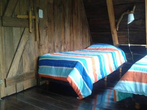 a bedroom with a bed with a striped blanket at Del Viejo Camino in El Bolsón