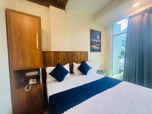 a bedroom with a large bed with blue pillows at Rio Rooms Calicut Near Mims Hospital in Kozhikode