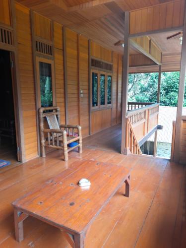 a porch of a wooden cabin with a wooden table at Pairi's Family Homestay in Rantepao