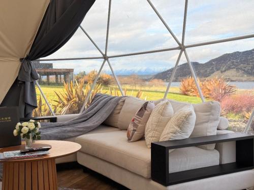 a living room with a couch and a large window at Glamping Dome - Rosé in Cromwell