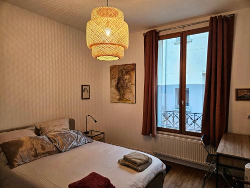 une chambre avec un lit, une fenêtre et un lustre dans l'établissement Charmant 3 pièces Rueil Malmaison cœur de ville, à Rueil-Malmaison