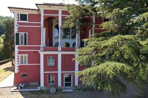 a red house with a tree in front of it at Albergo Palazzo Costa in Beverino