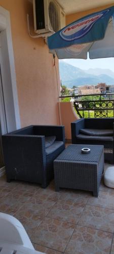 a balcony with two chairs and a table and an umbrella at Apartmani Relax D in Tivat