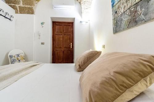 a bedroom with two beds and a wooden door at Nura's - Il Nido central old town Bastioni view in Alghero