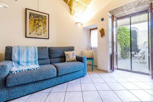 a living room with a blue couch and a sliding glass door at Nura's - Il Nido central old town Bastioni view in Alghero