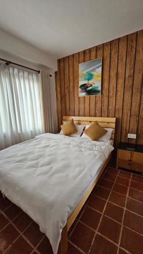 a bedroom with a large bed with white sheets at Yangla Home in Kathmandu