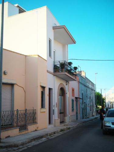 a street with a white building and a car at Le Panare Home in Spongano