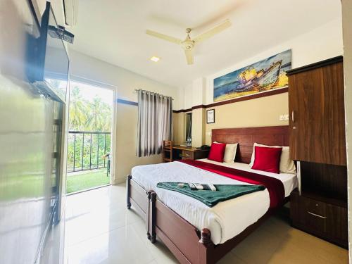 a bedroom with a bed with red pillows and a window at Rio Rooms Calicut Near Mims Hospital in Kozhikode