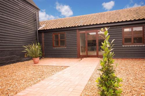 a house with a brick patio in front of it at The Cartshed in Wangford