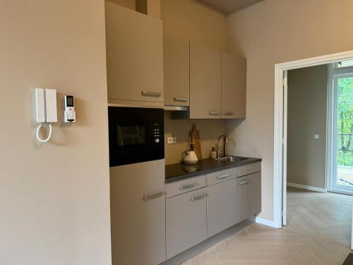 a kitchen with white cabinets and a black microwave at Naest - Authentic Escapes Grand House in Nijmegen