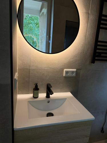 a bathroom sink with a round mirror above it at Naest - Authentic Escapes Grand House in Nijmegen