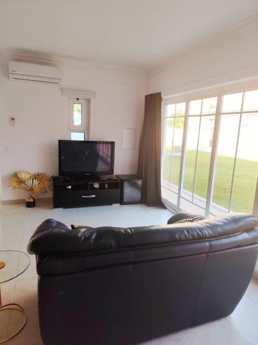a living room with a leather couch and a television at Verdizela Suites in Corroios